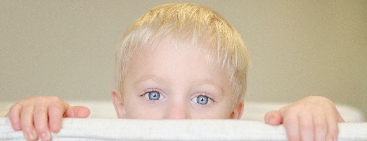 Nasalitätsstörung - Junge schaut hinter Sofa hervor